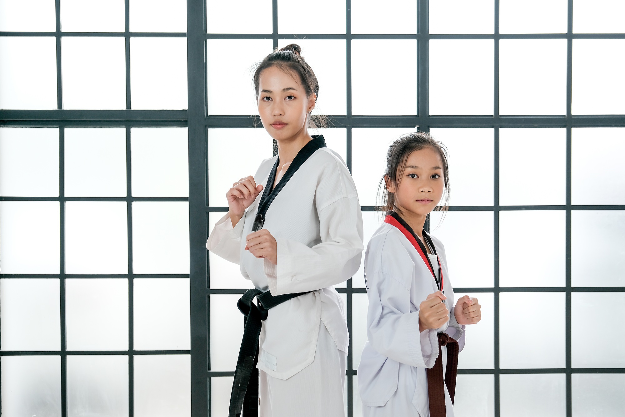 Young teacher of taekwondo and her student is acting of basic posture